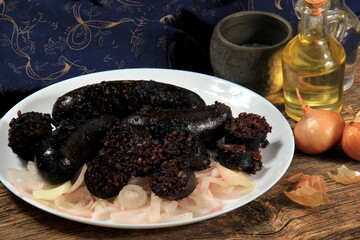 Baked black pudding with pickled onions on a white plate. Sliced and fried blood sausage on a plate