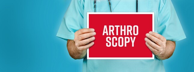 Arthroscopy. Doctor shows red sign with medical word on it. Blue background.