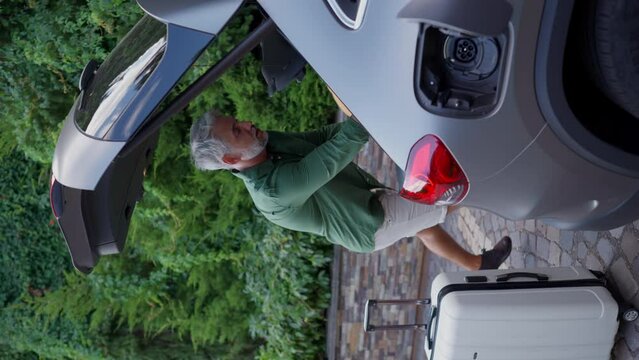 Couple charging electric car in frontyard driveway.