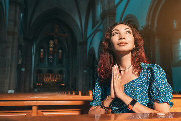 The girl prays in the Catholic Church and asks God for health, forgiveness of sins and finding...