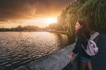 A student girl with a backpack stands near the embankment of Lake Aasee in Munster and enjoys a...