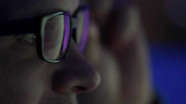 A programmer, a man in front of a computer, the code is reflected in the glasses. Working in IT, learning programming languages, developing applications and software.