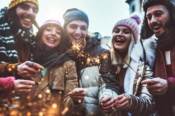 Close up image of happy friends enjoying out with sparklers - Group of young people celebrating new...