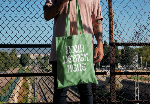 Man Holding a Tote Bag Mockup With Custom Colors and Design