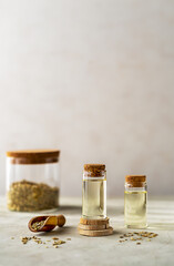 Two bottles of essential fennel oil with fennel seeds on light background - obrazy, fototapety, plakaty