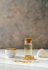 One bottle of essential fennel oil with fennel seeds on white and grey background. Vertical banner with copy space