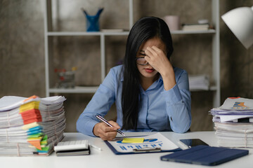 Asian female worker working overtime in the office late at night The girl is overworked and has...
