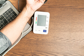 arm of a man taking his blood pressure and a laptop computer. Concept of health in people over 50