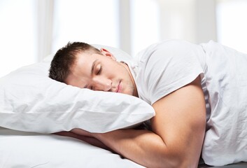 Obraz na płótnie Canvas Young sleeping man in bed, sleep in hotel concept