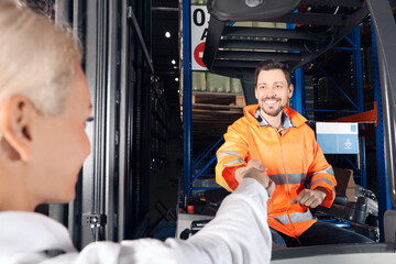 Happy worker shaking hands with manager in warehouse