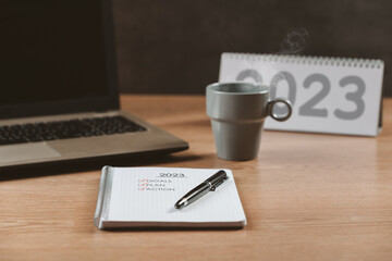Notebook with a to-do list for the year 2023, calendar, a laptop and a hot coffee - concept, goals and action plan, new year