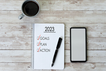 Coffee, smart phone and notebook with a to-do list for the year 2023 - concept, goals and action...