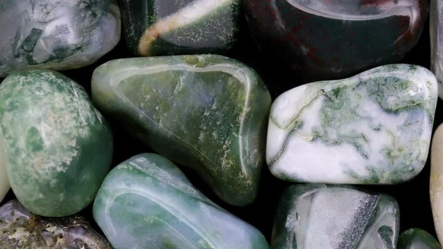 Moss agate heap jewel stones texture on white light background. Moving right seamless loop backdrop.