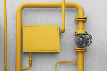 Gas meter box and pipes near grey wall outdoors