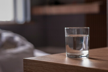 Glass of water on wooden table in room. Space for text