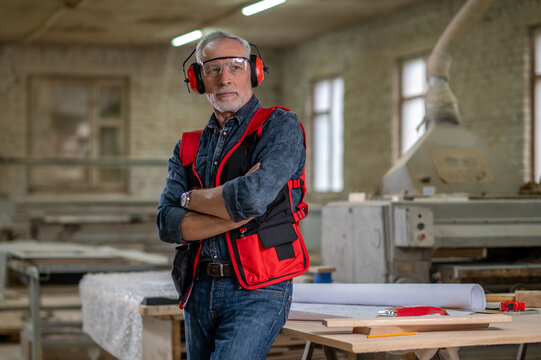 Mature Man In Eyeglasses And Ear Protector In A Workshop