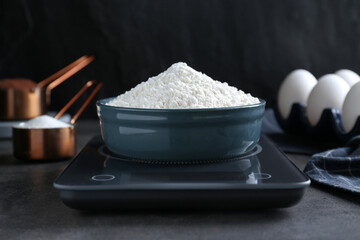 Electronic scales with flour on black table