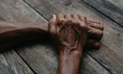 Old man's hands resting on wood.