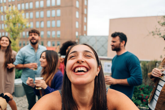 joyful happy young woman having fun and laughing naturally at the university rooftop students party with friends