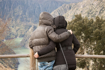 couple of lovers embraced watching the landscape on a cliff in galicia