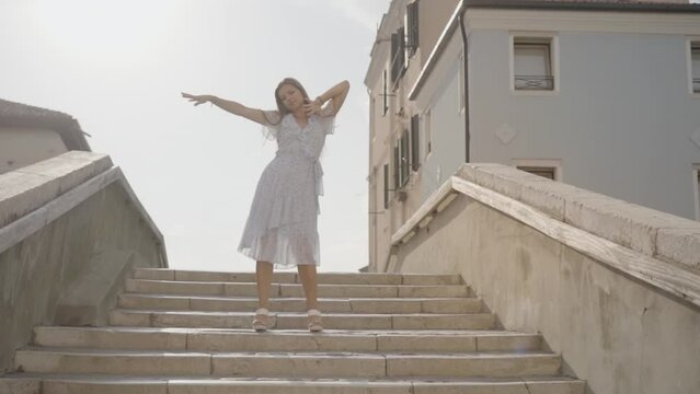 Young woman dances on the Venetian bridge in the summer sun