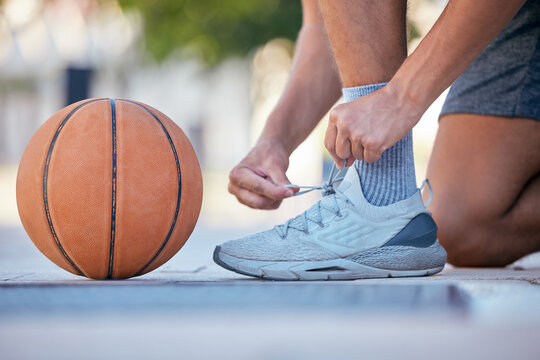 Basketball, sports and shoes with a man athlete tying his laces before a game on an outdoor court. Fitness, exercise and sport with a male basketball player fastening his shoelaces for a match
