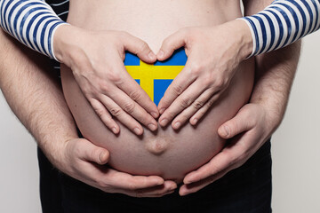 Swedish family concept. Man embracing pregnant woman belly and heart with flag of Sweden colors...