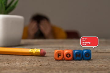 Fear of missing out concept: die composing the text fomo (fear of missing out) and a guy with hands...