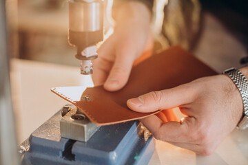 Male designer and leather tailor working at a factory close up