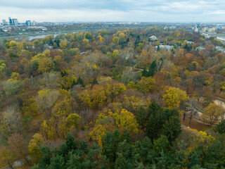 widok na panoramę Warszawy w pochmurny dzień, zachód słońca, z drona, znad jesiennych drzew w...