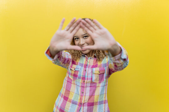 Smiling woman gesturing over yellow background