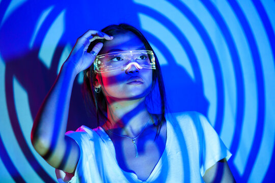 Thoughtful woman in smart glasses under spiral shadow