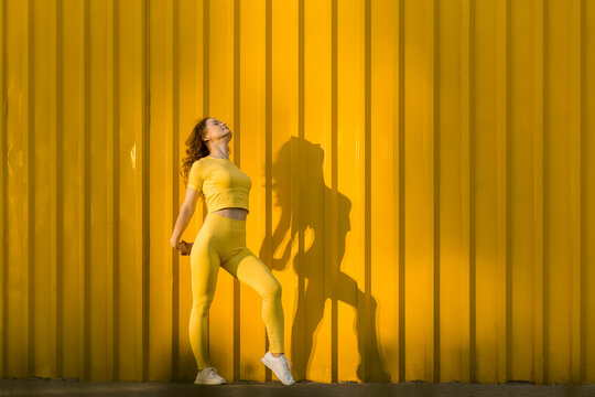 Woman stretching in front of yellow wall