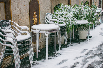 bar tables and chairs on the street with snow and ice