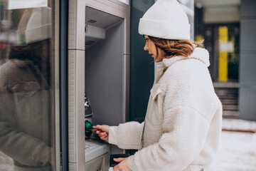 Woman withdrawing money at atm outside the street