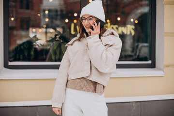 Young woman in winter time using phone outside the street