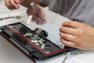 a man disassembles a laptop for repair and cleaning