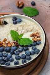 oatmeal porridge with ripe blueberries for healthy breakfast on rustic wooden board. close up Detox and healthy superfoods bowl concept