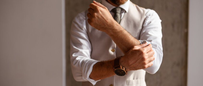Faceless shot of elegant businessman rolling sleeve of shirt in office, banner crop 
