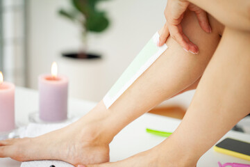 Obraz na płótnie Canvas Woman using beeswax stripe to shave her leg