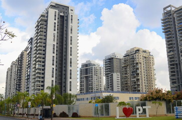 Obraz premium Modern residential area in Israel. Apartment buildings, housing stock, real estate for families. New buildings next to the park, palm trees and greenery