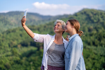 Backpack adventure hiking traveler mother and daughter on mountain use smartphone take picture