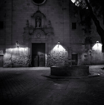 Black And White Photo Of Medieval Square At Night And Saint Philip Neri Church In Barcelona City Spain. Remains Of Spanish Civil War On The Facade.