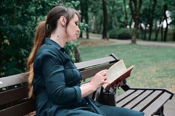 peaceful woman reading a book in the park. a woman in a relaxed atmosphere sits on a bench in the park.