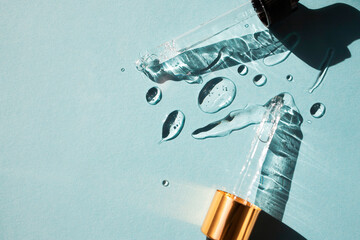 Drops of gel-like cosmetic liquid and glass pipettes on a blue background. Top view, place for text.