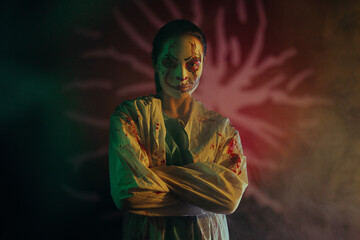 Portrait of young woman in image bloodthirsty zombie with horror wounds and bloody clothes in Halloween .