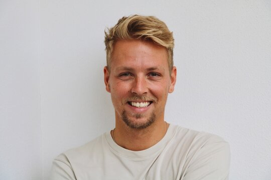 Blonde Guy Happy In Front Of White Wall