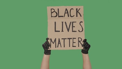 Female hands in black gloves pick up a poster from a cardboard box that reads BLACK LIVES MATTER. Struggle for equality and unity. Isolated on green screen, chroma key. © kinomaster