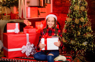 Obraz na płótnie Canvas Small cute girl with gift box near christmas tree. Winter present. Present concept. Child enjoy celebration new year present. Season to giving presents for loved ones. Spread love. Kindness concept