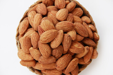 grains of natural dry brown almonds in a decorative plate on a white background